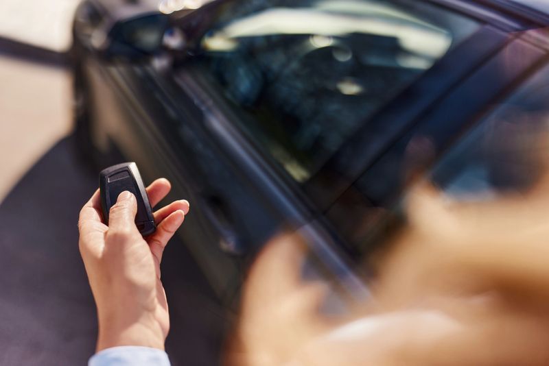 Close up of unrecognizable woman using a key to lock her car on the street.