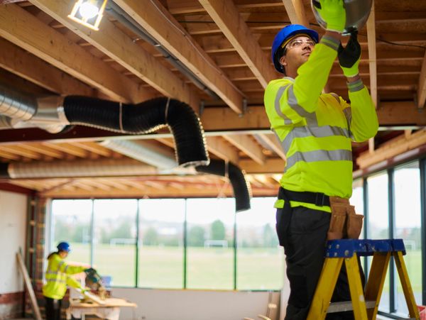 Construction workers installing ductwork in a building under renovation.