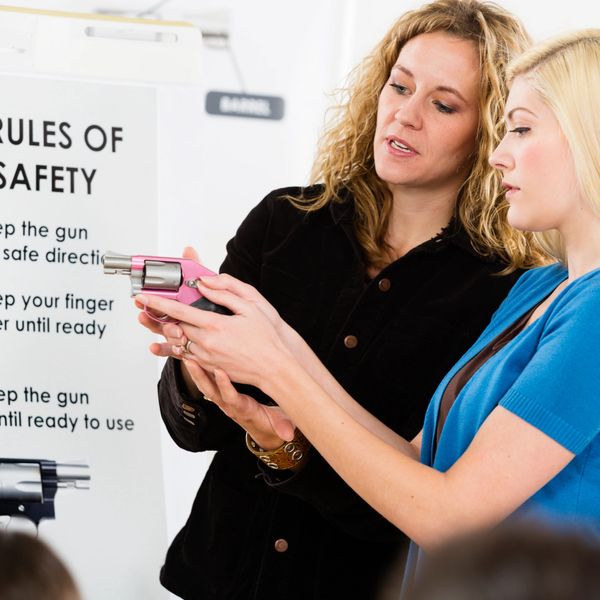 Instructor teaching a woman gun safety handling with a pink revolver.