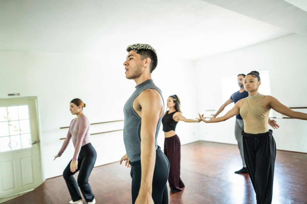 Group of dancers practicing a routine in a bright studio.