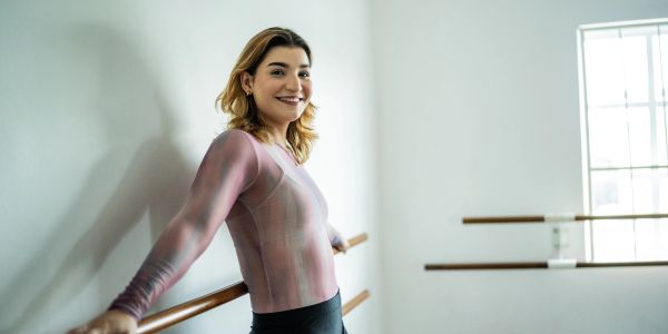 Bailarina sonriente en estudio de danza con barra.
