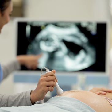 A medical professional performing an ultrasound on a pregnant woman.