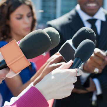 Reporters holding microphones during an interview.