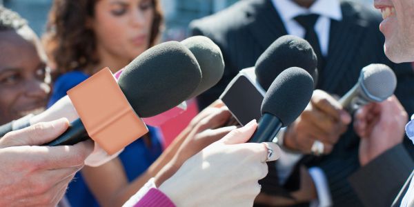 Reporters holding microphones during an interview.