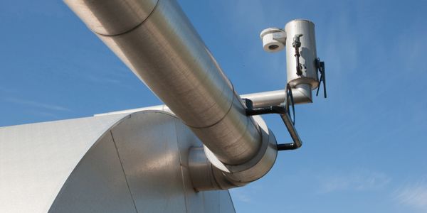 Close-up of a large metallic telescope against a clear blue sky.