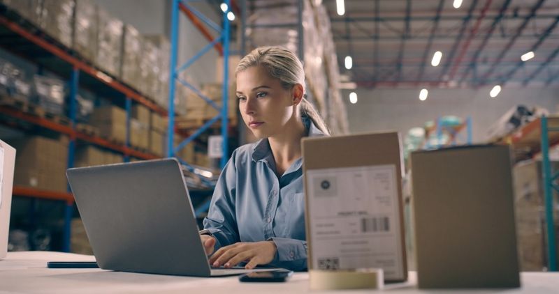 Business woman, laptop and box in supply chain, logistics or management in shipment control at warehouse. Female person or storage manager working on computer in export, inspection or distribution