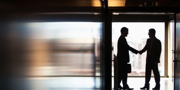 Two businessmen shaking hands in a hallway.