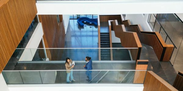 Two people talking in a modern office building corridor.