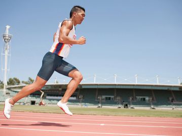 Athlete sprinting on a track during daytime.