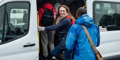 People boarding a white van in cold weather.
