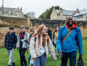 A group of people walking and chatting outdoors near historic buildings.