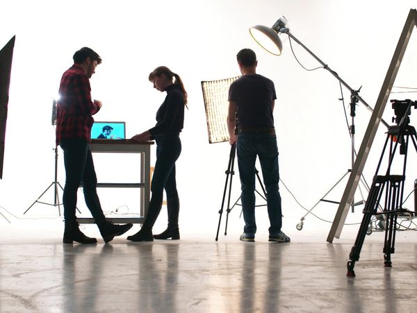 Three people working with cameras and lighting in a studio.