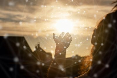 Hand reaching towards the glowing sun with a network pattern overlay.