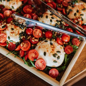 Fresh tomato salad with grilled cheese and seeds in a wooden tray.
