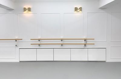 Minimalist ballet studio with wooden barres and white paneled walls.