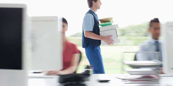 A man walking in an office carrying a stack of packages.