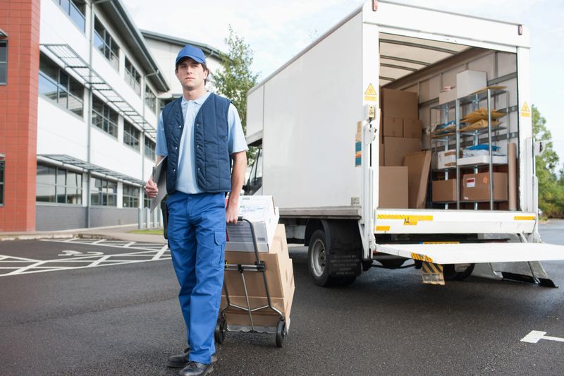 Deliveryman puling boxes on hand truck