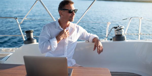 Man in sunglasses on a boat with a laptop.