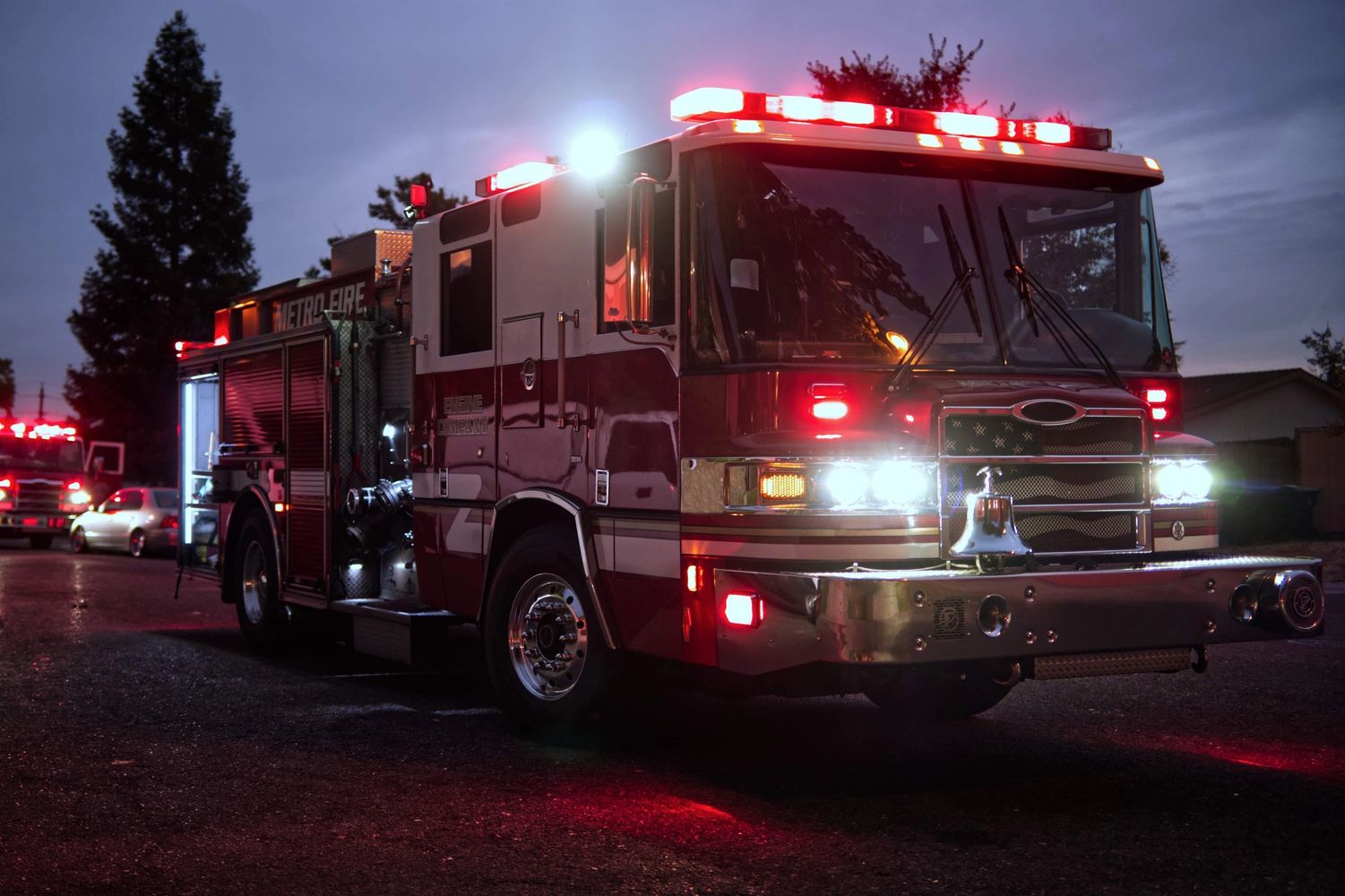 Fire truck with flashing lights at dusk on a street.