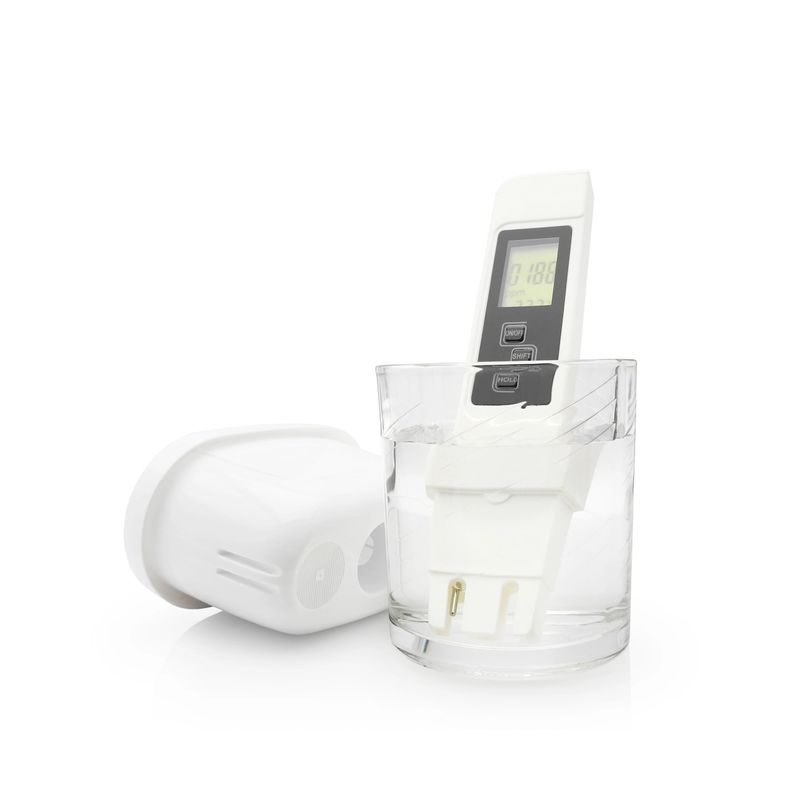 Water quality meter tester with display in transparent glass near plastic cartridge for filter jugs isolated on white background. Measuring harmful impurities, purifying water for healthy drinking.