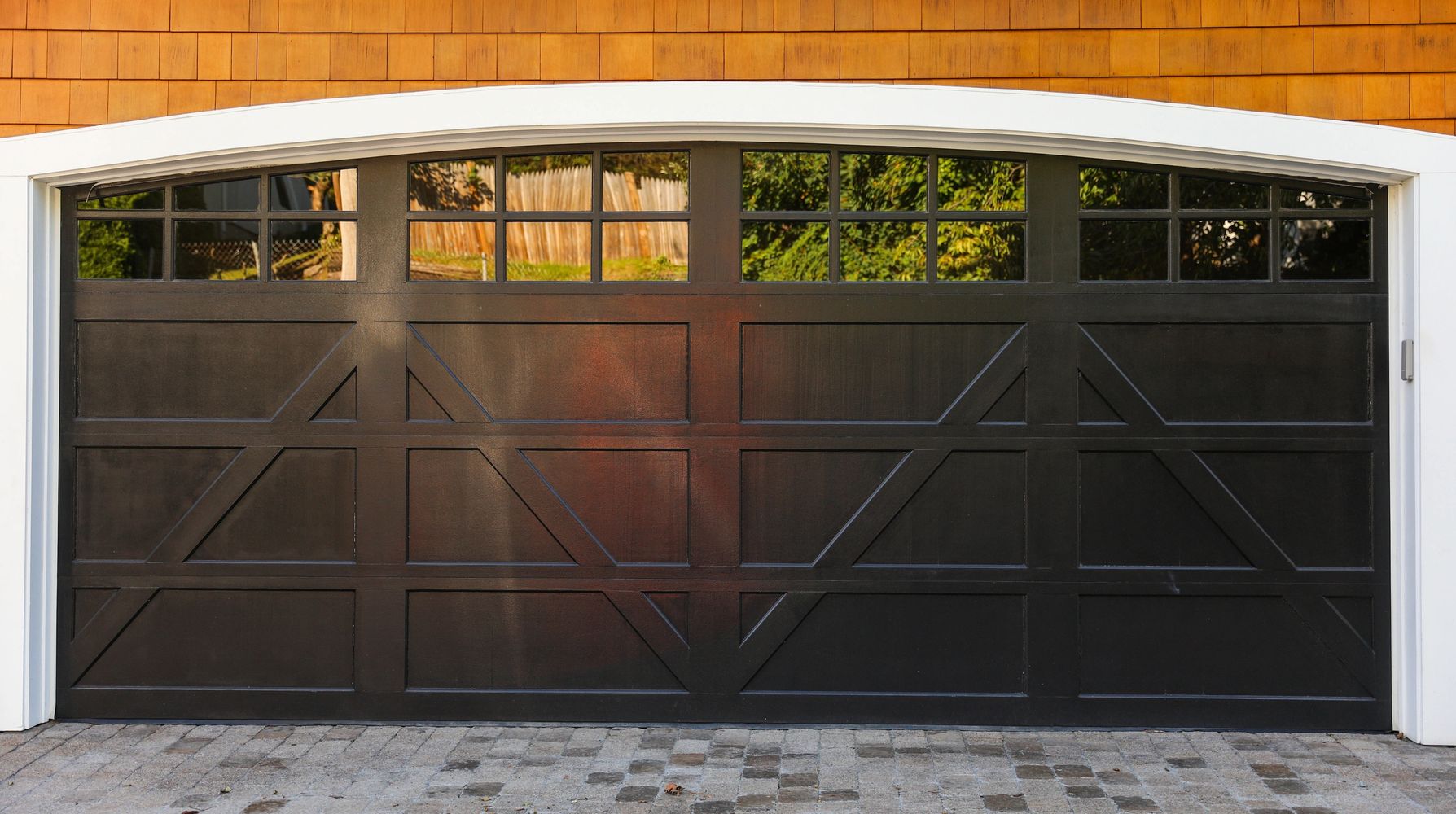Modern black garage door with small windows on top.