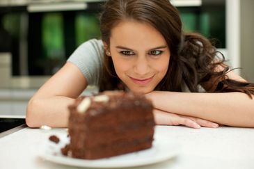 Smiling woman looking at a chocolate cake slice.