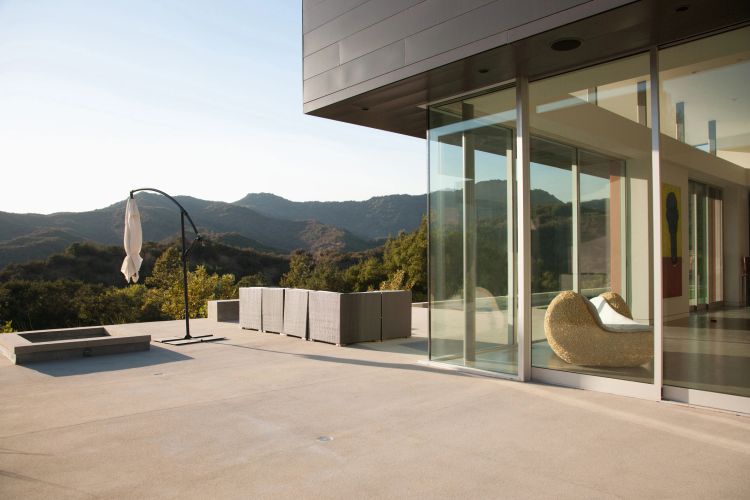 Modern outdoor kitchen with grill, sink, and wooden cabinetry.