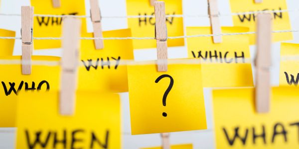 Yellow sticky notes with question words clipped on a line.