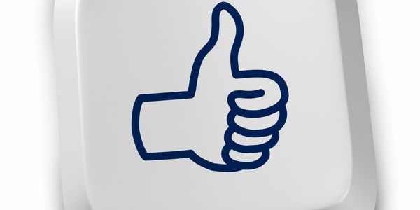 Computer key with thumbs-up icon symbolizing approval or like.