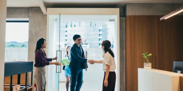 Two professionals shaking hands in a modern office lobby.