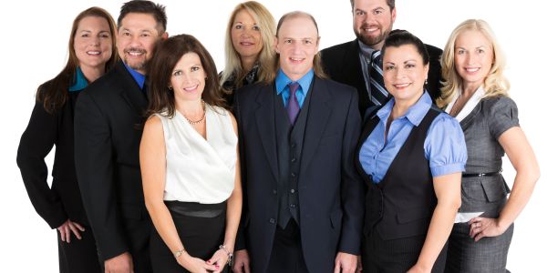 Group of eight professionally dressed businesspeople posing together.