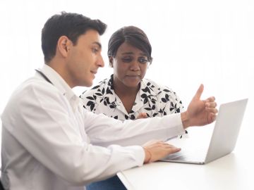 A doctor explaining medical information to a patient using a laptop.