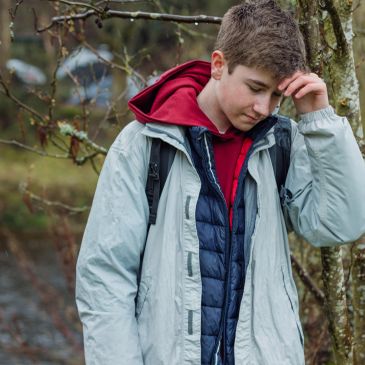 A young man outdoors in layered jackets.