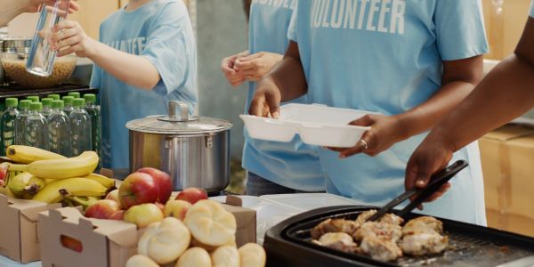Volunteers serving food and packing meals at a community event.