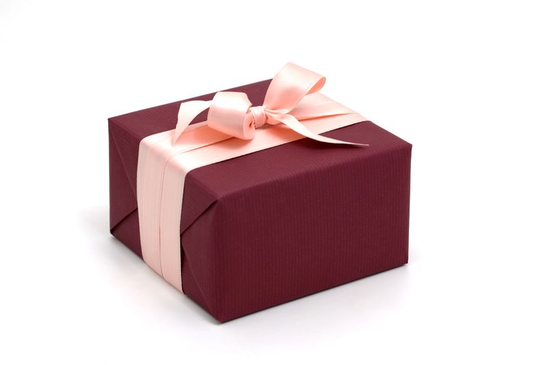 close-up of a dark red wrapped gift box with pink ribbon and bow