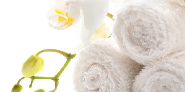 Rolled white towels with blooming white orchids for a spa setting.