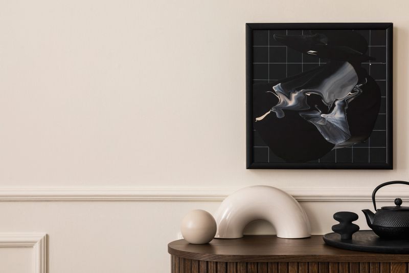 Minimalist composition of living room interior with mock up poster frame, copy space, wooden sideboard, stylish sculpture, black pitcher, trace and personal accessories. Home decor. Template.