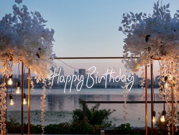 Birthday setup with lights and flowers by the water.