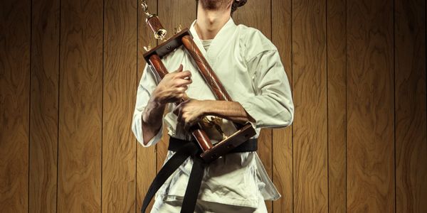 Martial artist proudly holding a large trophy.