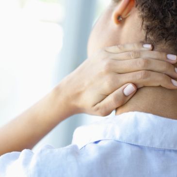 Person holding the back of their neck in discomfort.