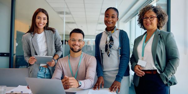 Four diverse professionals smiling in a modern office.