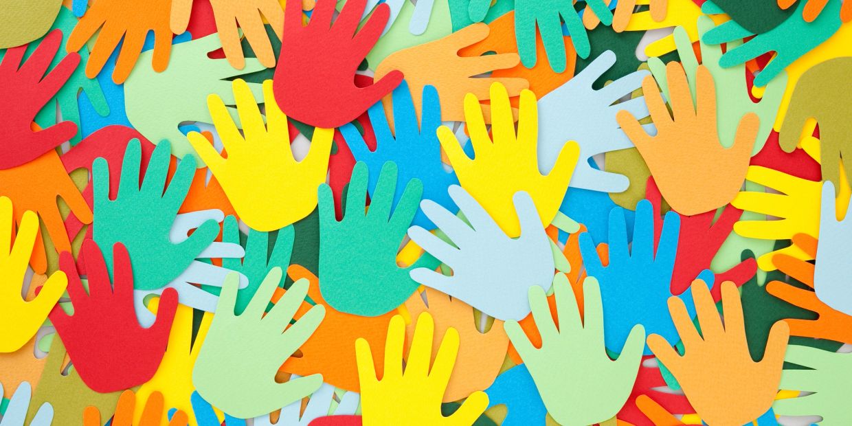 Colorful paper cutouts of hands overlapping in a vibrant pattern.