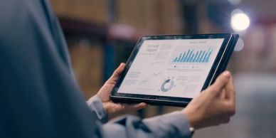Person holding a tablet displaying data charts and graphs.