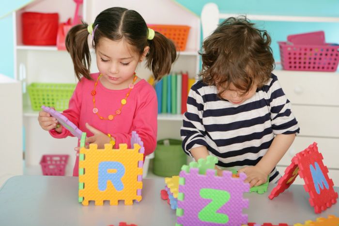 Two children playing with colorful foam puzzle pieces.