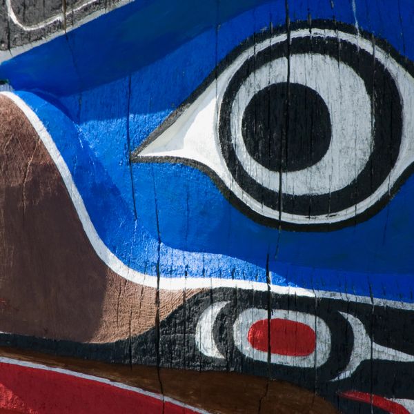 Close-up of Native American totem pole with blue and black painted eye.