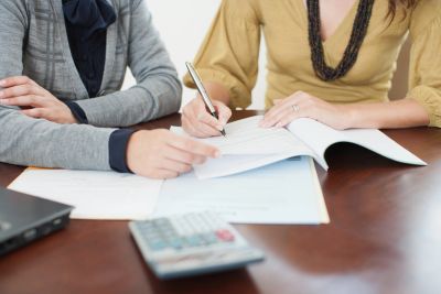 Two people reviewing documents and signing papers.