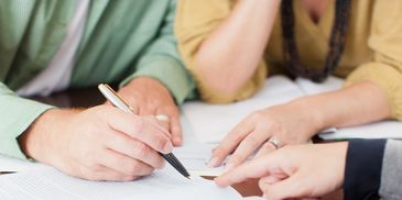 People signing a document together.