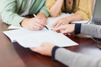 People signing and reviewing documents at a table.