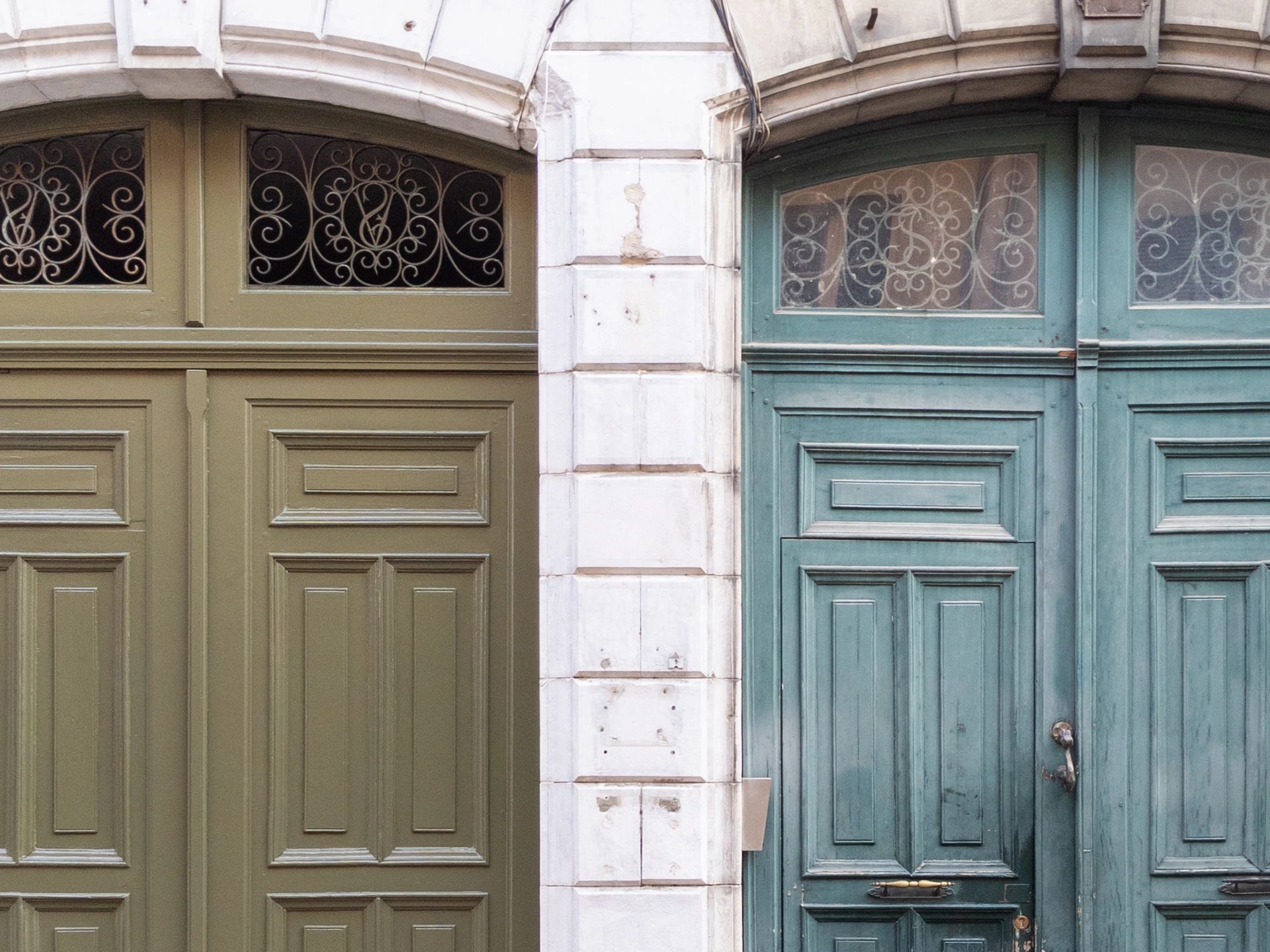 Two large, old wooden doors side by side with decorative glass panels above.
