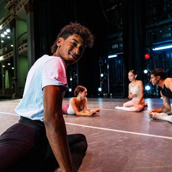 Ballet dancers stretching on stage before rehearsal.